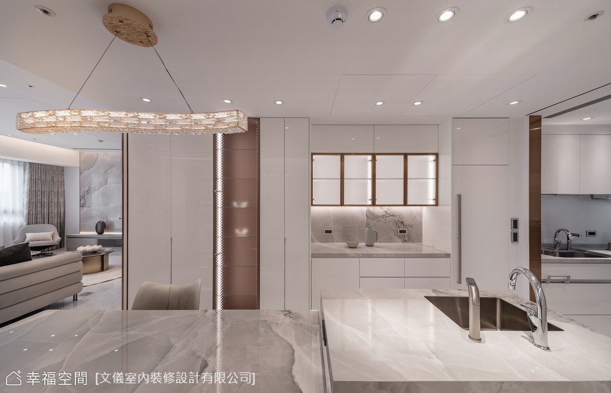 此設計展現現代風格,透過開放式格局連接客廳與廚房,並利用大理石中島與特色吊燈,營造出寬敞且精緻的空間