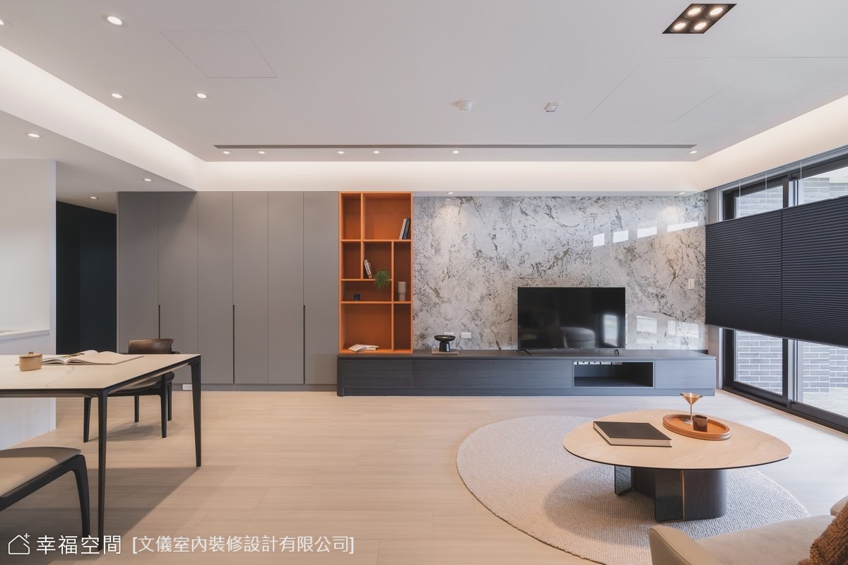 開放式設計的現代風格客廳,透過灰色大理石電視牆與橘色收納櫃跳色,營造簡潔時尚的居家氛圍。