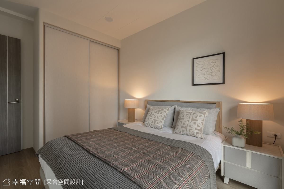 這間現代風格臥室以淺色木質元素營造溫馨氛圍,搭配灰色寢具與收納櫃,提供舒適且實用的休憩空間。(圖/幸福空間-采舍空間設計)