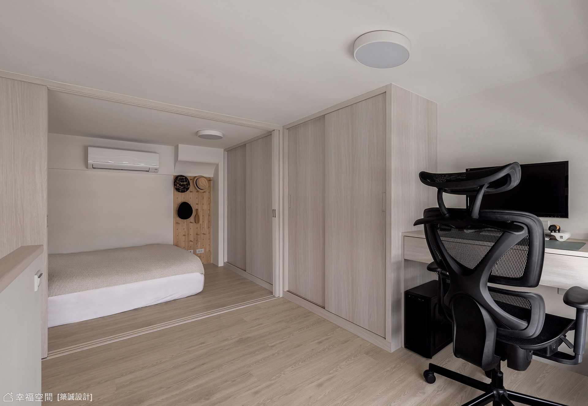此現代風臥室結合書房機能,以淺色木紋與白色調營造明亮舒適氛圍,並透過推拉門區隔出睡眠與工作區域,達到