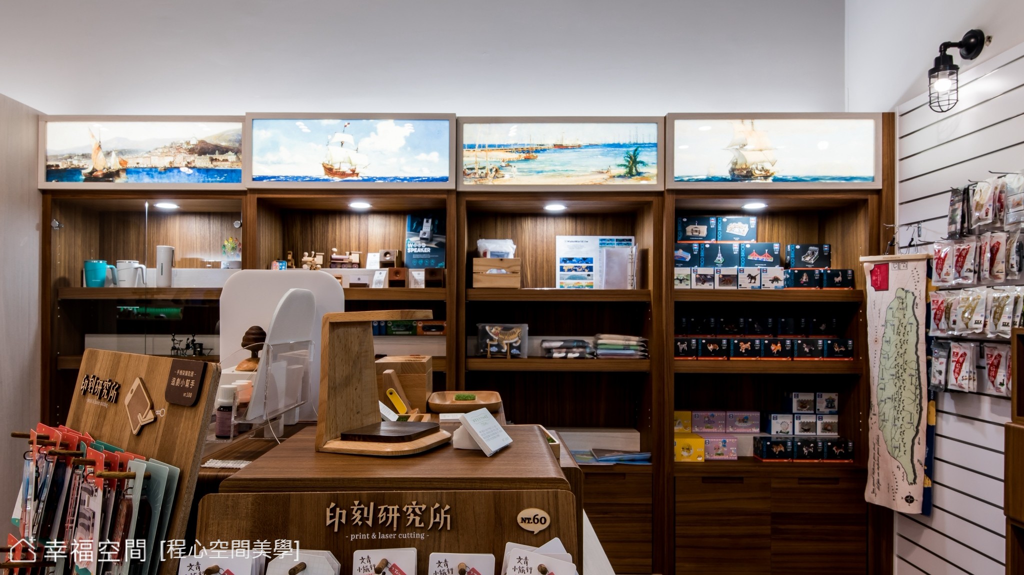 此商用空間以現代風格為主,運用木質展示櫃與燈光營造溫暖氛圍,搭配海上風景畫作點綴。