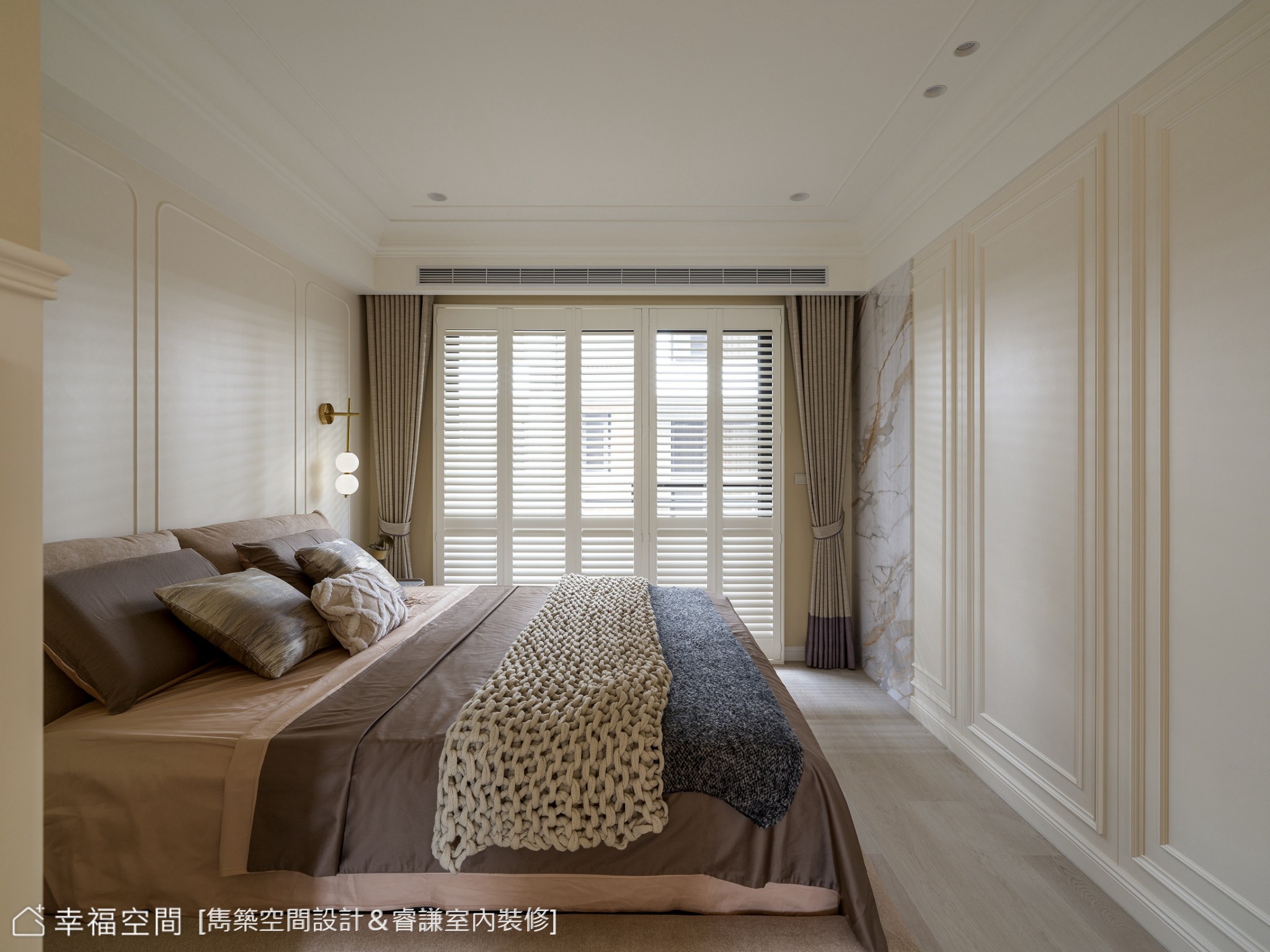 現代風格臥室以白色線板與大理石牆面營造優雅氛圍，搭配咖啡色寢具與金色壁燈，提升整體設計質感。